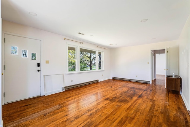 interior space with wood-type flooring, baseboard heating, a baseboard radiator, and baseboards