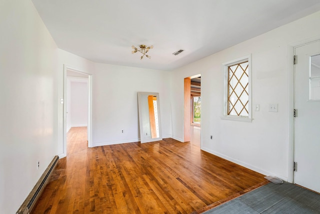 interior space featuring visible vents, a baseboard radiator, baseboards, and wood finished floors