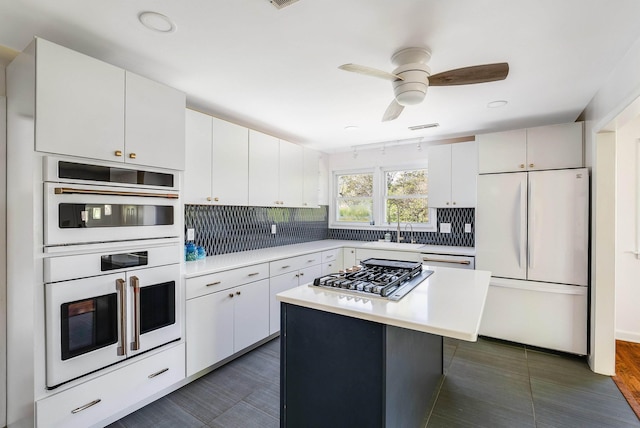 kitchen with a sink, backsplash, light countertops, and white appliances