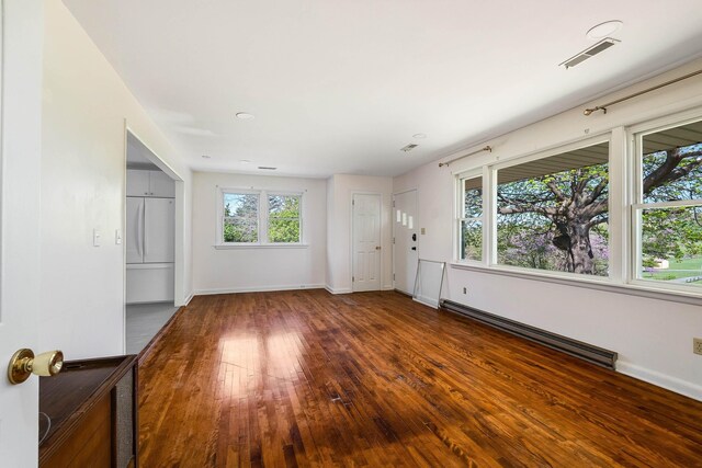 spare room featuring visible vents, a baseboard radiator, hardwood / wood-style floors, and baseboards