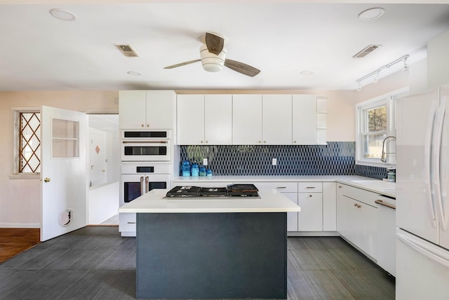 kitchen featuring visible vents, a sink, light countertops, a ceiling fan, and white appliances