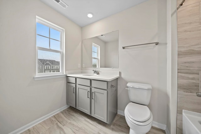 bathroom with vanity, toilet, baseboards, and visible vents