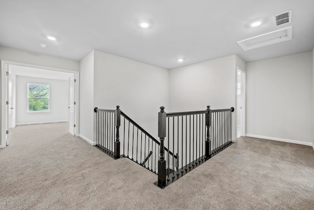 hallway featuring an upstairs landing, visible vents, baseboards, and carpet floors