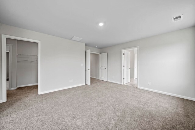 unfurnished bedroom with visible vents, baseboards, a spacious closet, and carpet flooring