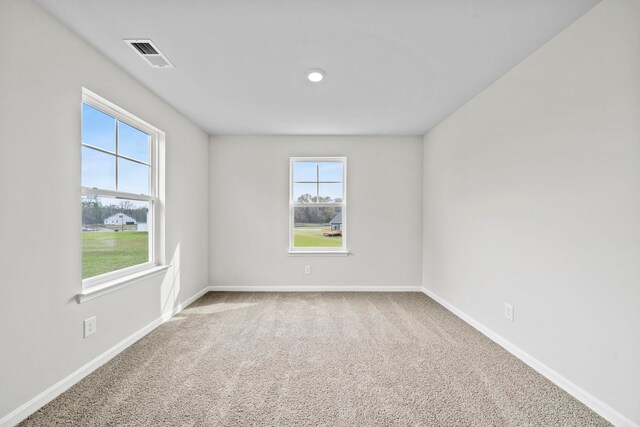 empty room with visible vents, plenty of natural light, baseboards, and carpet flooring