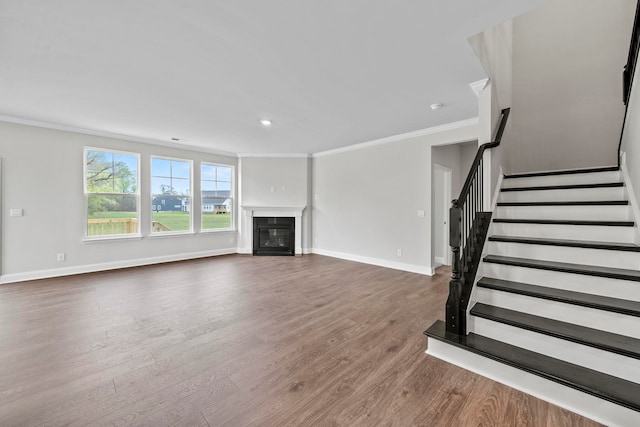 unfurnished living room with baseboards, stairway, ornamental molding, wood finished floors, and a glass covered fireplace