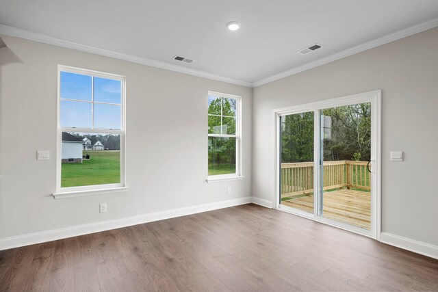 spare room with wood finished floors, visible vents, and ornamental molding