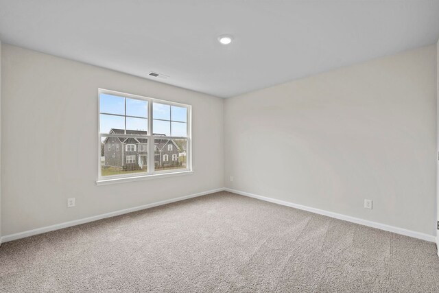 carpeted empty room featuring visible vents and baseboards