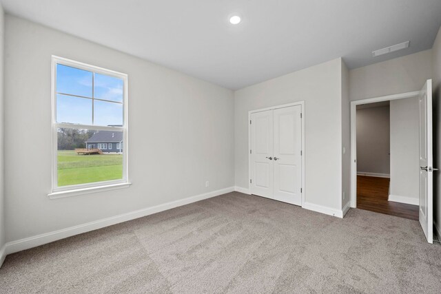 unfurnished bedroom featuring carpet, visible vents, baseboards, recessed lighting, and a closet