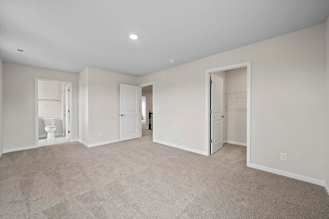 unfurnished bedroom with a spacious closet, visible vents, baseboards, and carpet floors