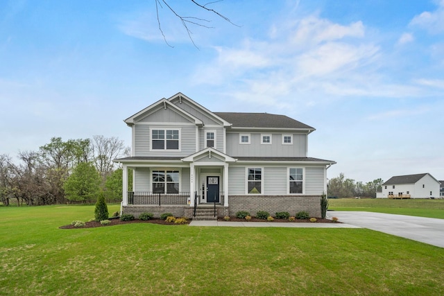 view of front of property featuring a front yard, driveway, covered porch, board and batten siding, and brick siding