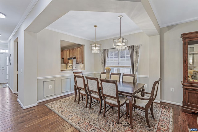 dining space featuring a notable chandelier, baseboards, dark wood-type flooring, and ornamental molding