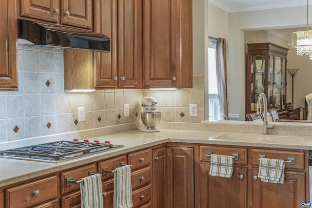 kitchen featuring brown cabinets, a sink, stainless steel gas stovetop, and extractor fan
