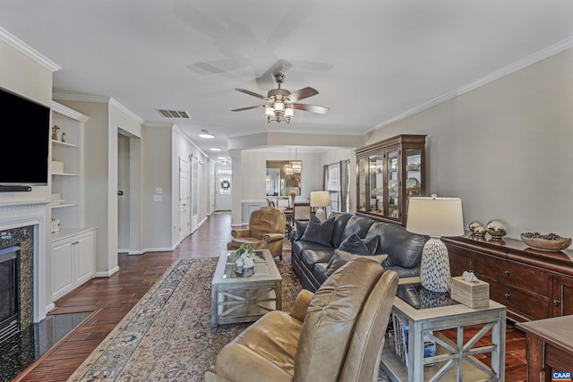 living room with ceiling fan, a premium fireplace, dark wood finished floors, ornamental molding, and visible vents