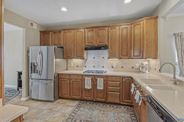 kitchen with a sink, appliances with stainless steel finishes, light countertops, under cabinet range hood, and visible vents