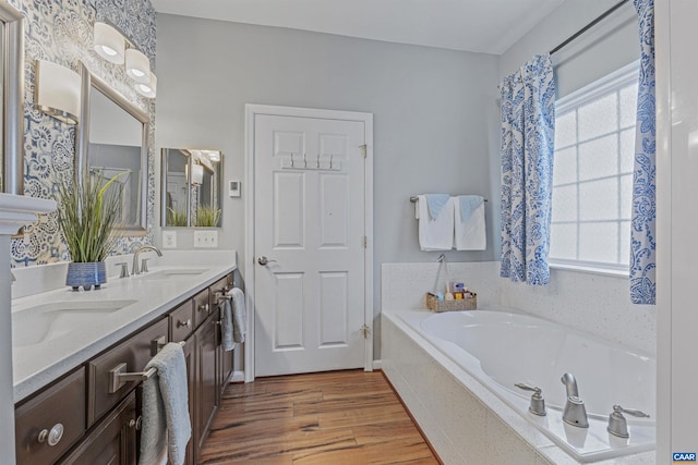 full bath with a garden tub, wood finished floors, a sink, and double vanity