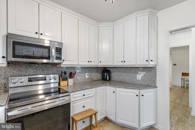 kitchen with white cabinets, backsplash, appliances with stainless steel finishes, and light stone counters