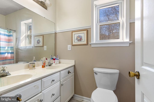 bathroom featuring a sink, toilet, and double vanity