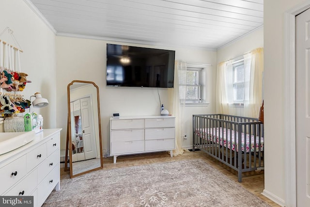 bedroom featuring a crib, crown molding, and baseboards