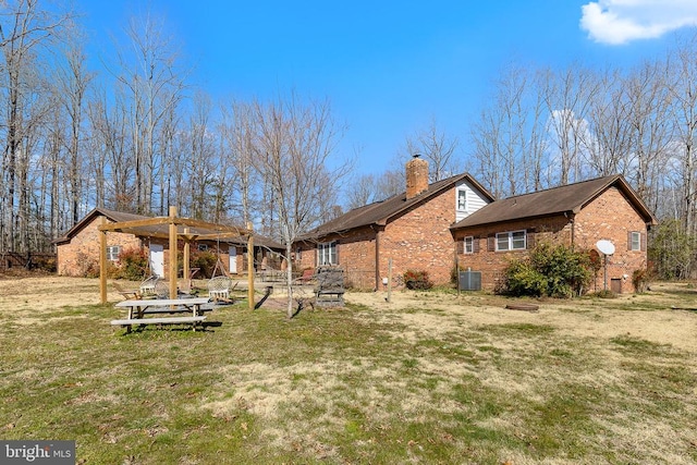 rear view of property with a lawn, central AC unit, brick siding, and a chimney