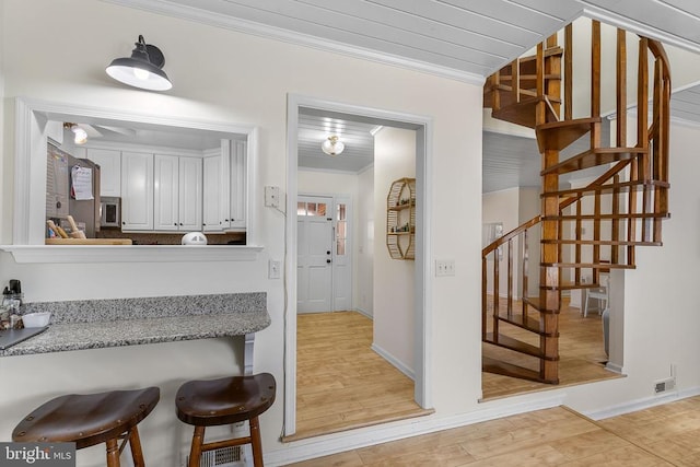 interior space featuring light wood finished floors, light countertops, crown molding, and white cabinetry