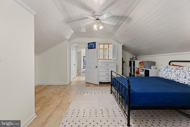 bedroom featuring baseboards, wood finished floors, crown molding, and vaulted ceiling