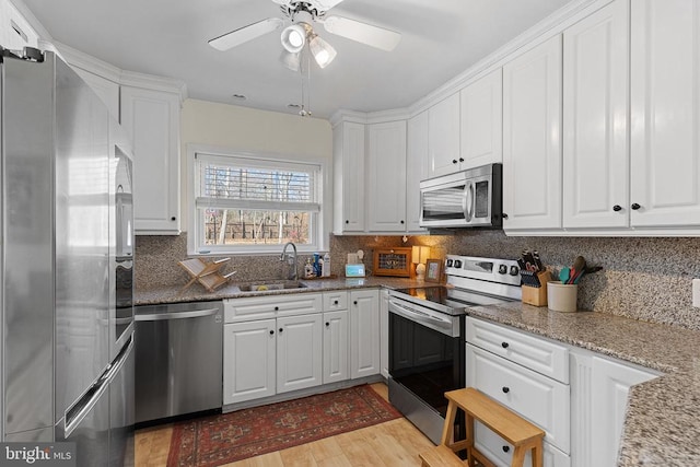 kitchen featuring a sink, stainless steel appliances, decorative backsplash, and white cabinetry