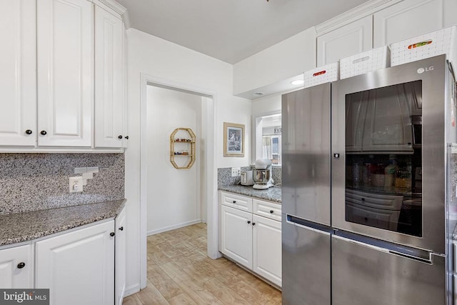 kitchen featuring light stone counters, light wood finished floors, tasteful backsplash, and white cabinetry