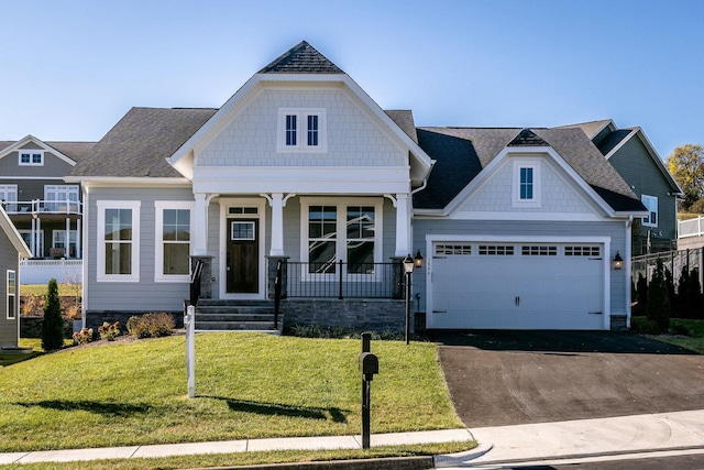 craftsman house featuring a shingled roof, covered porch, an attached garage, driveway, and a front lawn