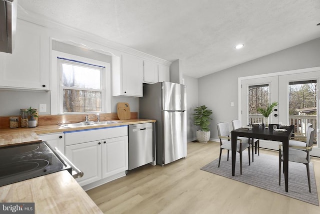 kitchen with stainless steel appliances, vaulted ceiling, light countertops, and a sink