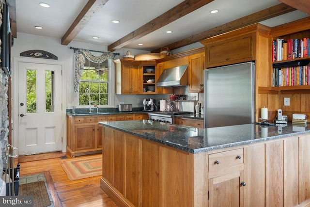 kitchen featuring built in fridge, stove, dark stone countertops, and wall chimney exhaust hood