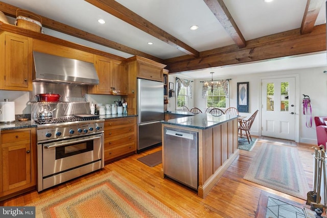 kitchen with pendant lighting, high quality appliances, extractor fan, light hardwood / wood-style floors, and a kitchen island