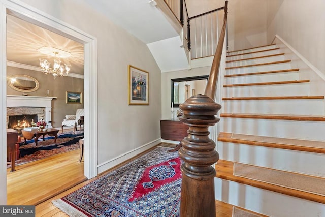 stairway featuring crown molding, wood-type flooring, a chandelier, and vaulted ceiling