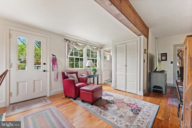 foyer featuring baseboard heating, beam ceiling, and light hardwood / wood-style flooring