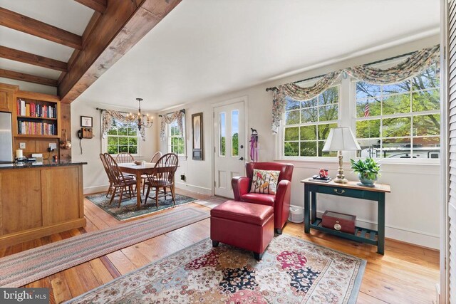 living room featuring beam ceiling, an inviting chandelier, and light wood-type flooring