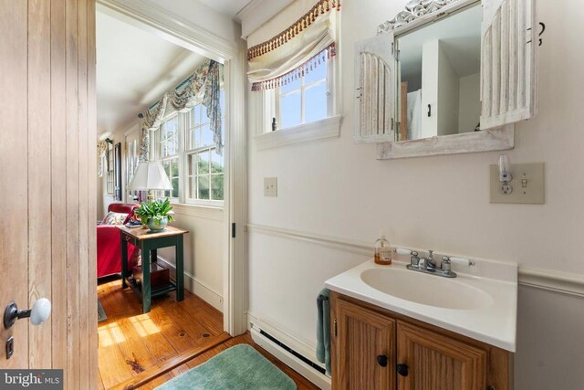 bathroom with a baseboard radiator, hardwood / wood-style floors, and vanity