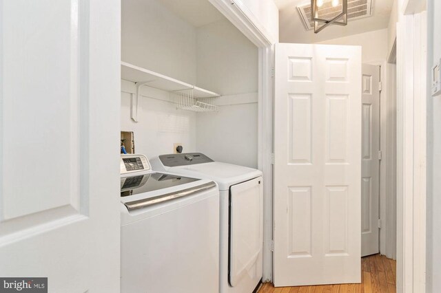 clothes washing area featuring washing machine and clothes dryer and light wood-type flooring