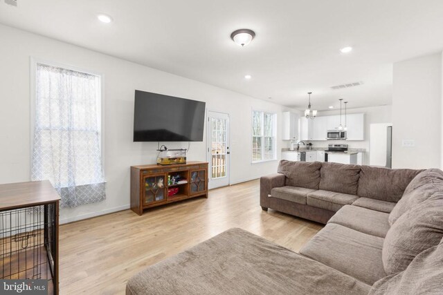 living room with recessed lighting, light wood-type flooring, baseboards, visible vents, and a notable chandelier