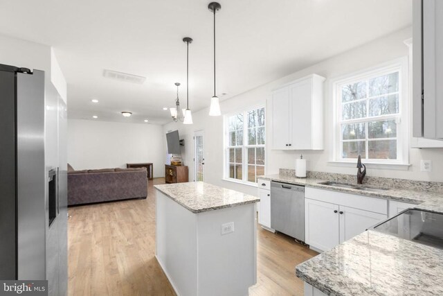 kitchen with stainless steel dishwasher, light wood-type flooring, a sink, and a kitchen island