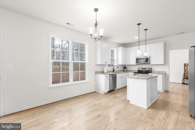 kitchen featuring white cabinetry, light wood-type flooring, appliances with stainless steel finishes, and an inviting chandelier