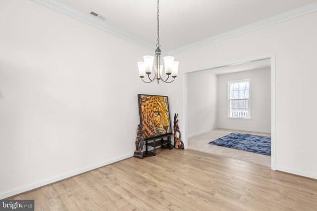 unfurnished dining area featuring baseboards, wood finished floors, a chandelier, and crown molding