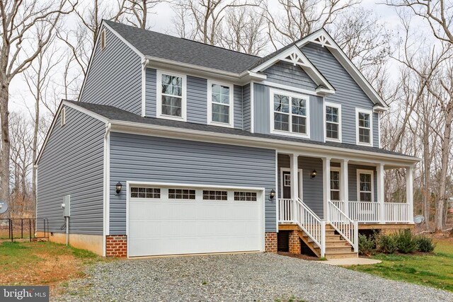 view of front of home featuring an attached garage, covered porch, and gravel driveway