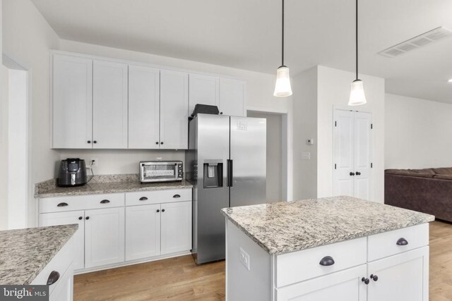 kitchen featuring light wood-style flooring, visible vents, stainless steel fridge, and a toaster