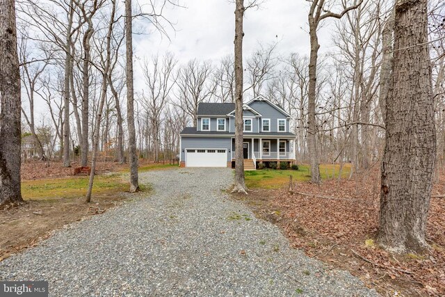 traditional home featuring gravel driveway, a porch, and a garage