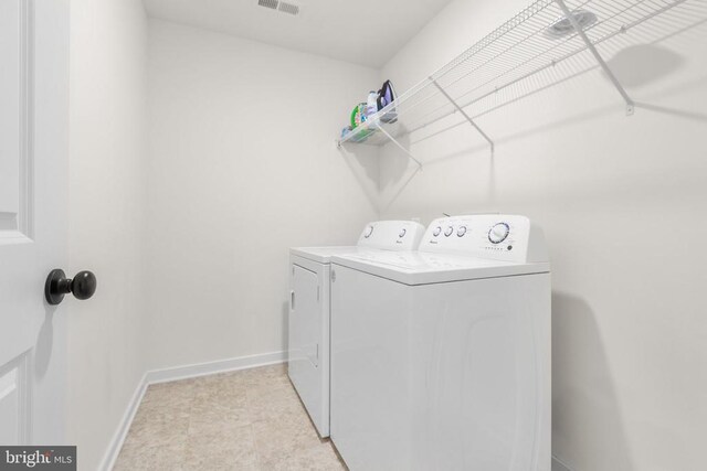 washroom with baseboards, laundry area, and separate washer and dryer