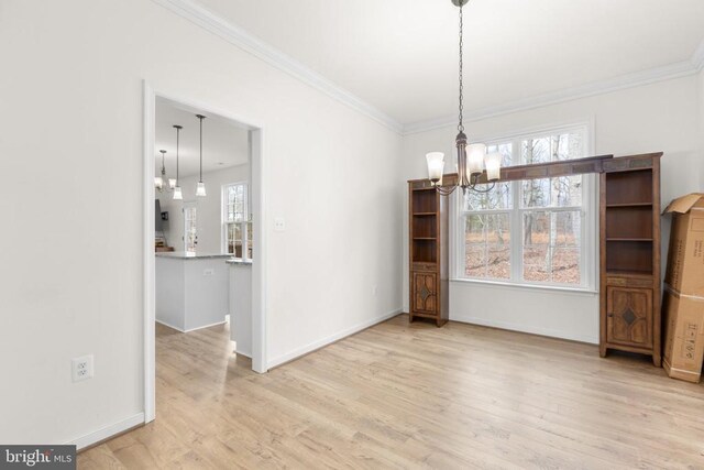 unfurnished dining area with baseboards, ornamental molding, wood finished floors, and a notable chandelier