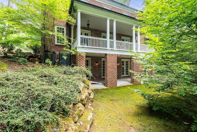 rear view of property featuring a balcony and a patio area