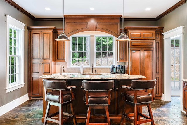 kitchen featuring a breakfast bar, sink, light stone counters, a center island, and pendant lighting