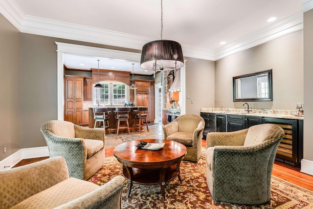 living room featuring wine cooler, ornamental molding, light hardwood / wood-style flooring, and wet bar