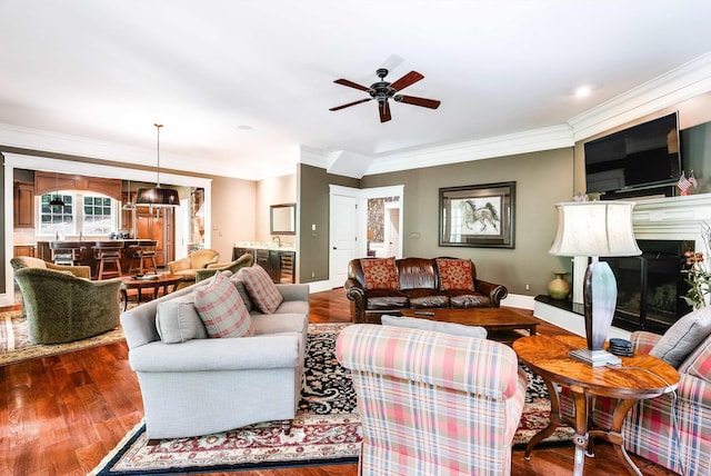 living room with wood-type flooring, sink, ceiling fan, and crown molding